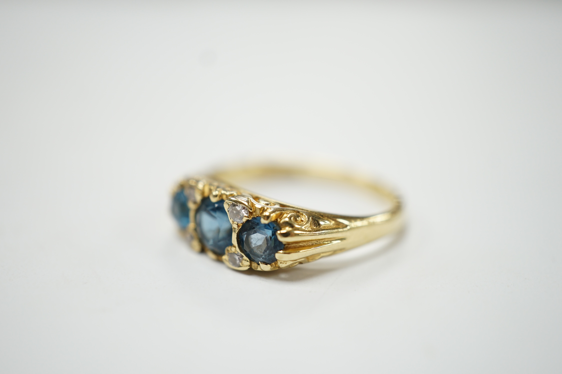 A modern Edwardian style 18ct gold and three stone blue topaz set ring, with diamond chip spacers, size M, gross weight 4.1 grams. Fair condition.